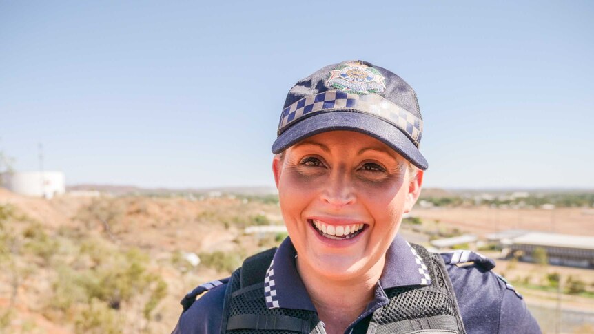 A smiling Acting Senior Constable Aimee Sewell of the Mount Isa police stands at a lookout over the town.