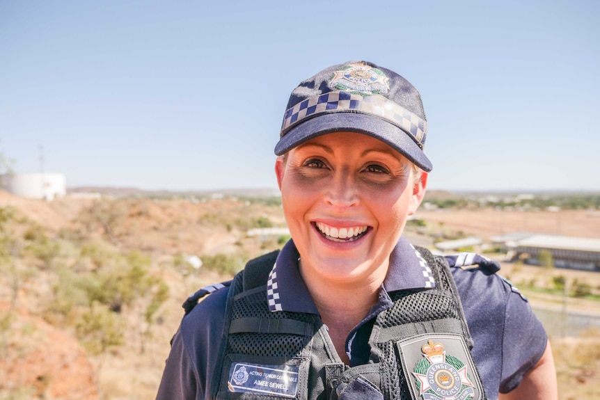 A smiling Acting Senior Constable Aimee Sewell of the Mount Isa police stands at a lookout over the town.