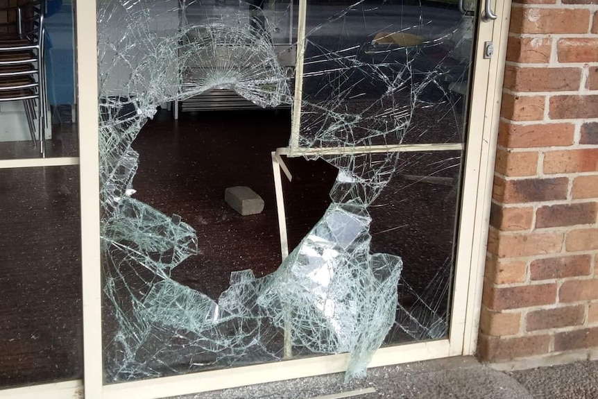 A smashed glass door in front of a cafe.