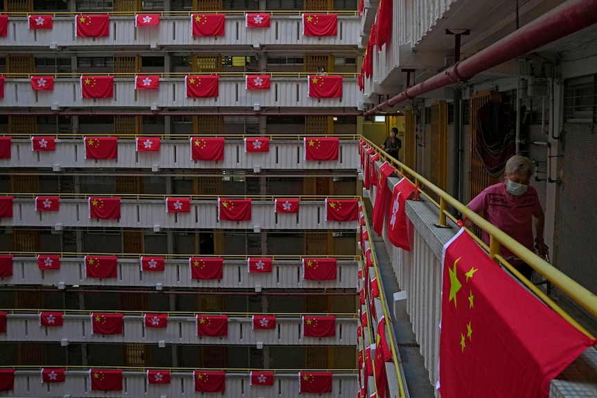 A resident walks past the Chinese and Hong Kong flags hanging from balconies