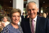 Jane Prentice, wearing a white and blue checked dress, smiles for a photo with Malcolm Turnbull, sporting a mauve patterned tie.