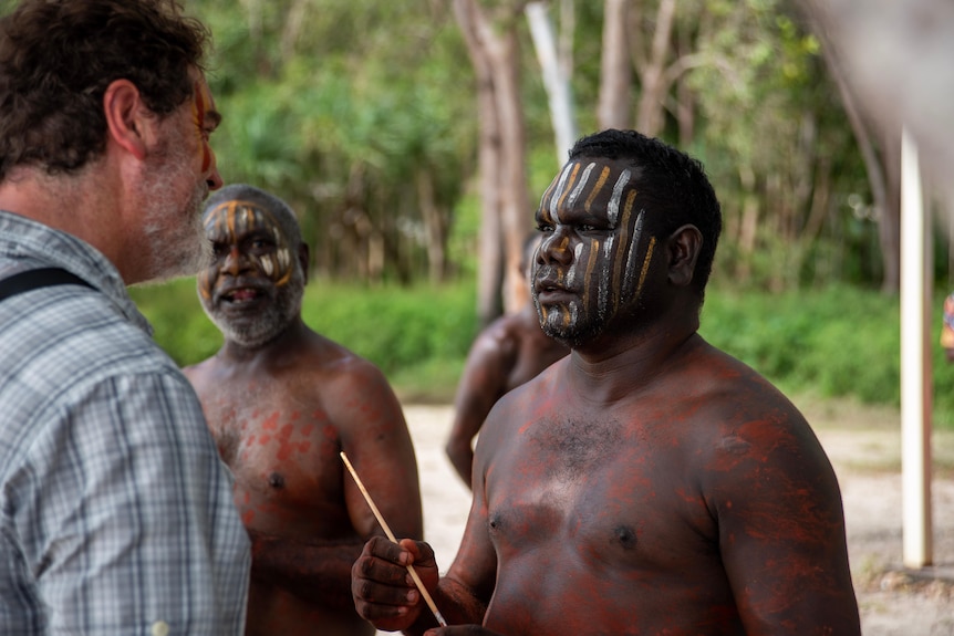 A man paints another mans face ahead of a cultural dance at Melville Island
