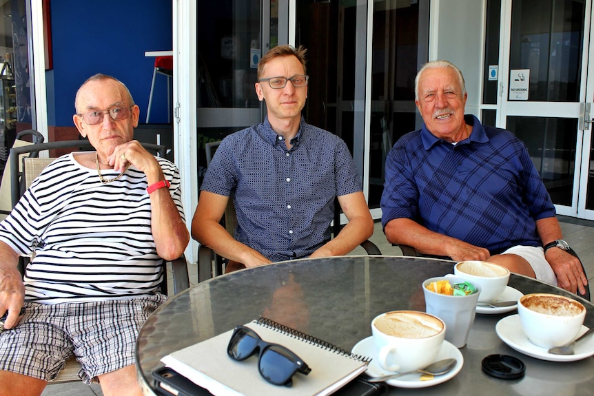 Three Italian gentlemen sitting at a coffee table looking directly to the camera.