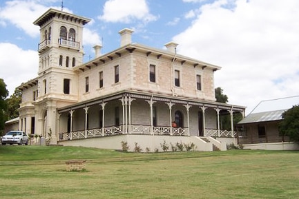 A large, luxurious cream and pink estate building surrounded by lawn.