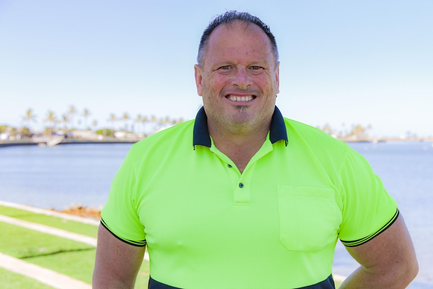 A man in high vis smiles at the camera 