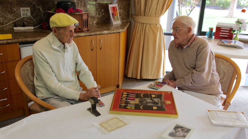 Two elderly men sitting at a table.