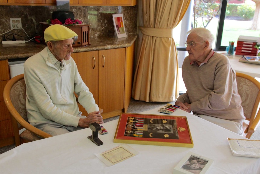 Two elderley men sitting at a table.