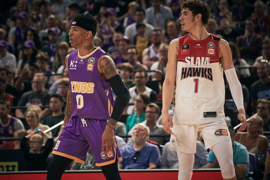 LaMelo Ball stands on court in front of a packed crowd.