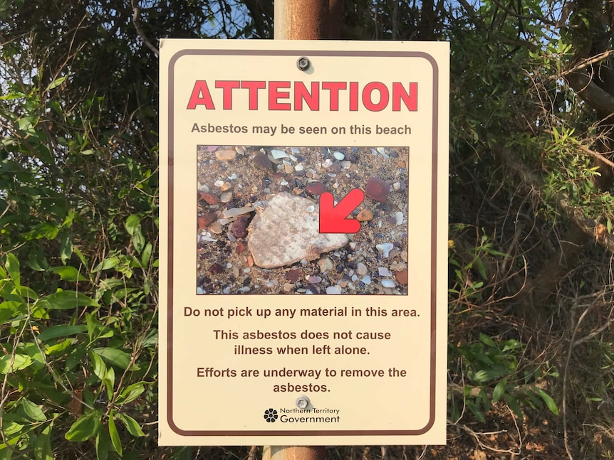 A sign with a photo of asbestos warning residents not to touch it at a beach.
