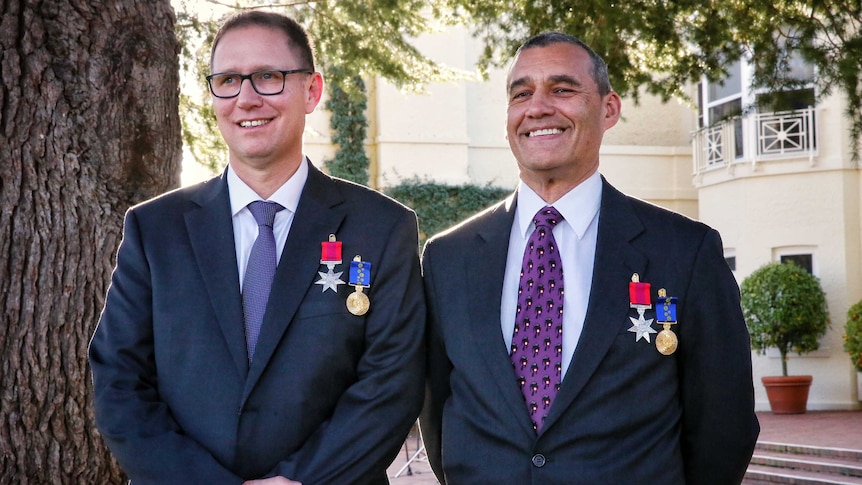 Richard Harris and Craig Challen, standing outside wearing their medals, smile.