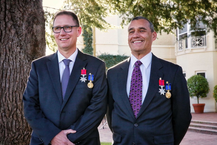 Richard Harris and Craig Challen, standing outside wearing their medals, smile.