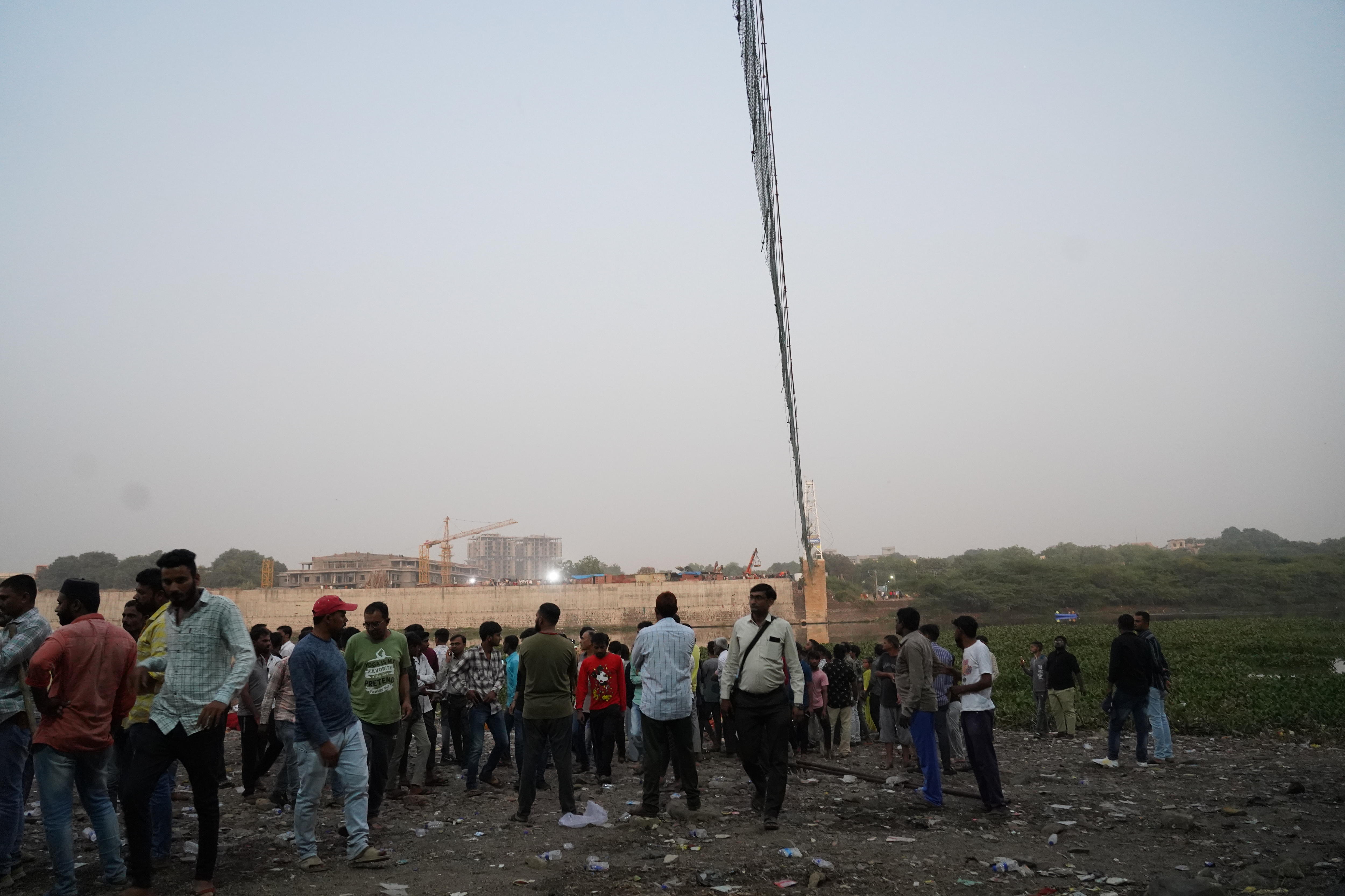 A group of people stands next to the river looking for missing people.