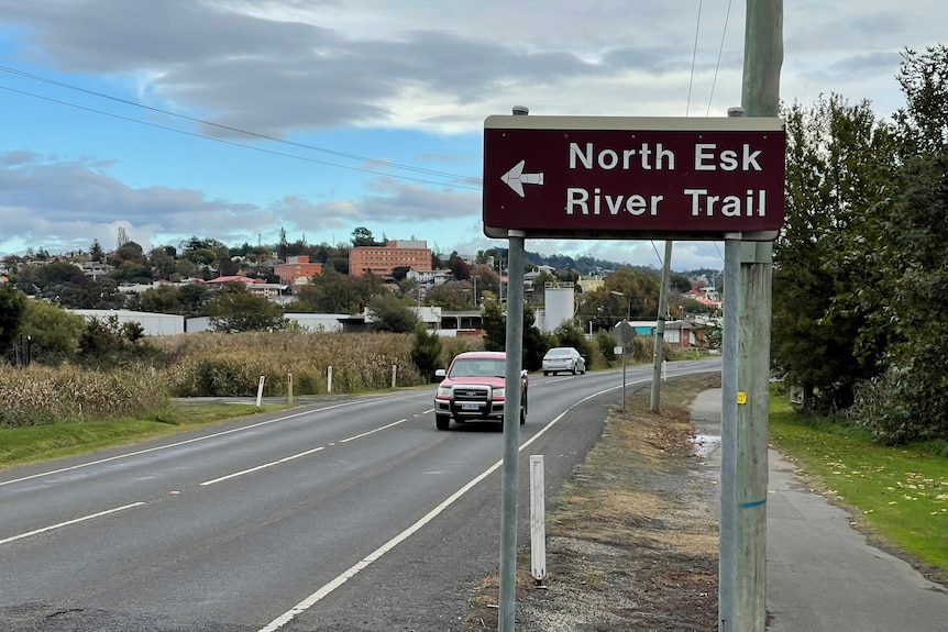 A street sign next to a two-lane road