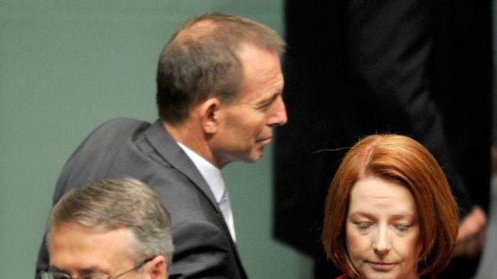 Tony Abbott walks behind Julia Gillard