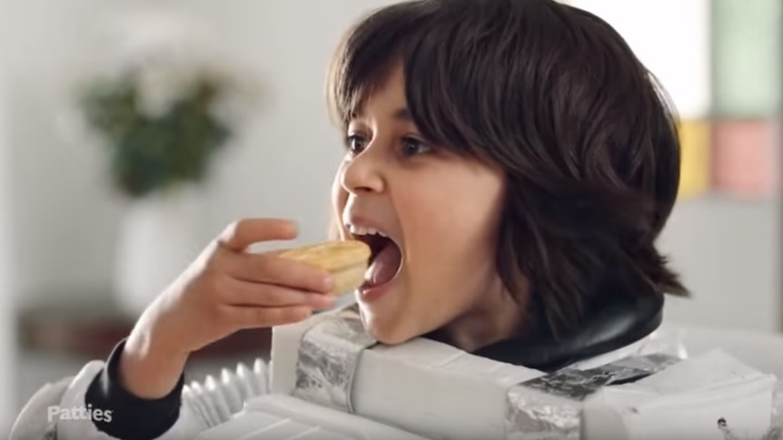 A boy eats a party pie in an advertisement for Patties.
