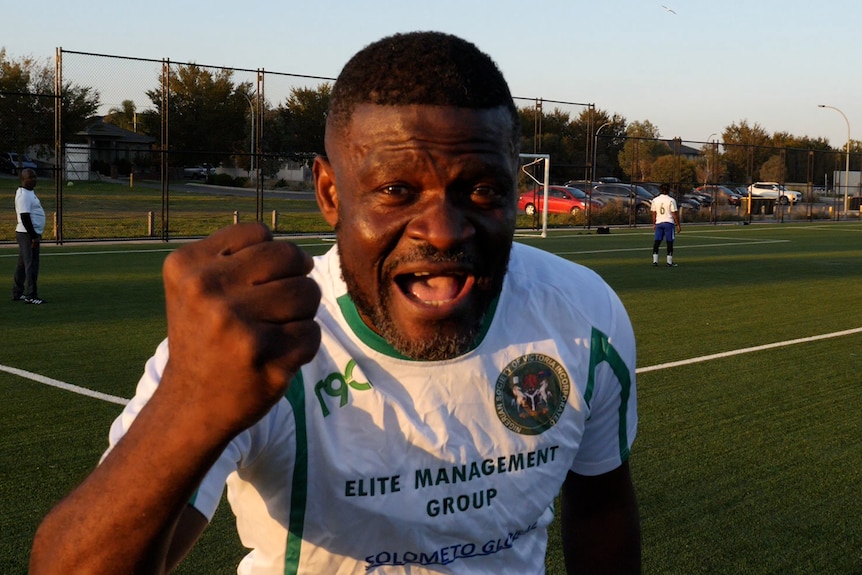 A close up of a Nigerian fan in a white shirt on a synthetic field.