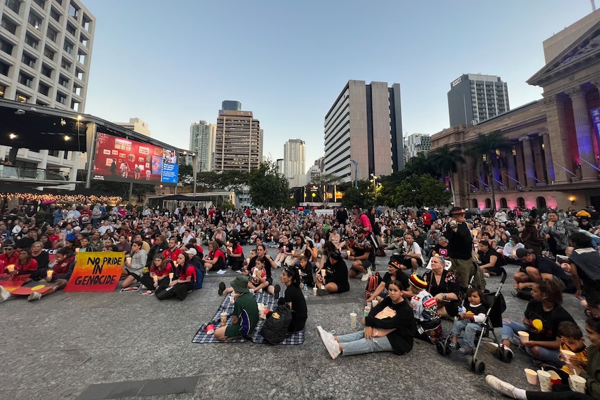 More than 1,000 people sitting on the ground at King George Square in Brisbane.