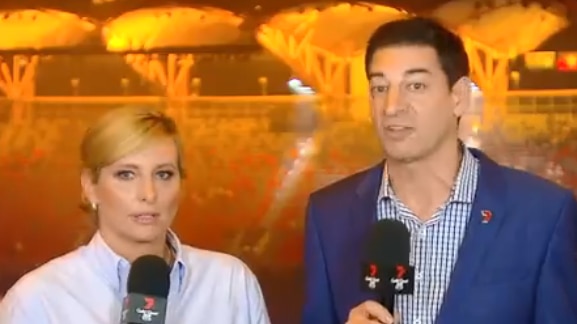 Hosts Johanna Griggs and Basil Zempilas stand together, stadium in the background.