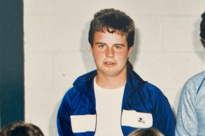 A young man dressed in a blue sweat jacket and white t-shirt.
