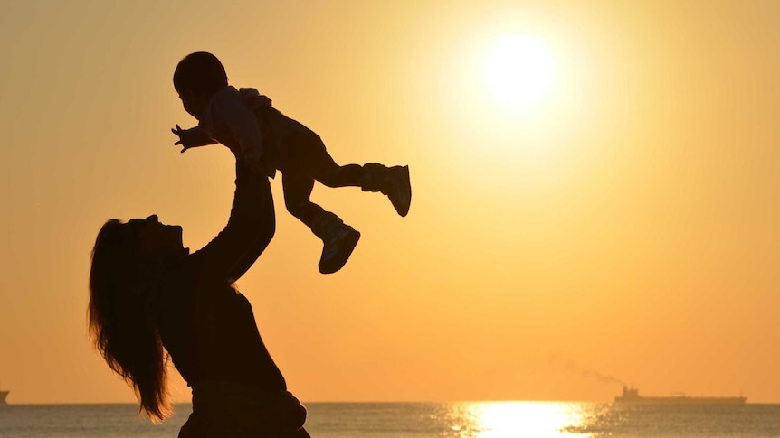 Silhouette of woman holding child in the air for a story about how people dealt with motherhood indecision.