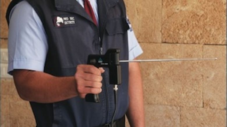 A security guard holds an ADE 651 'magic wand' bomb detector.