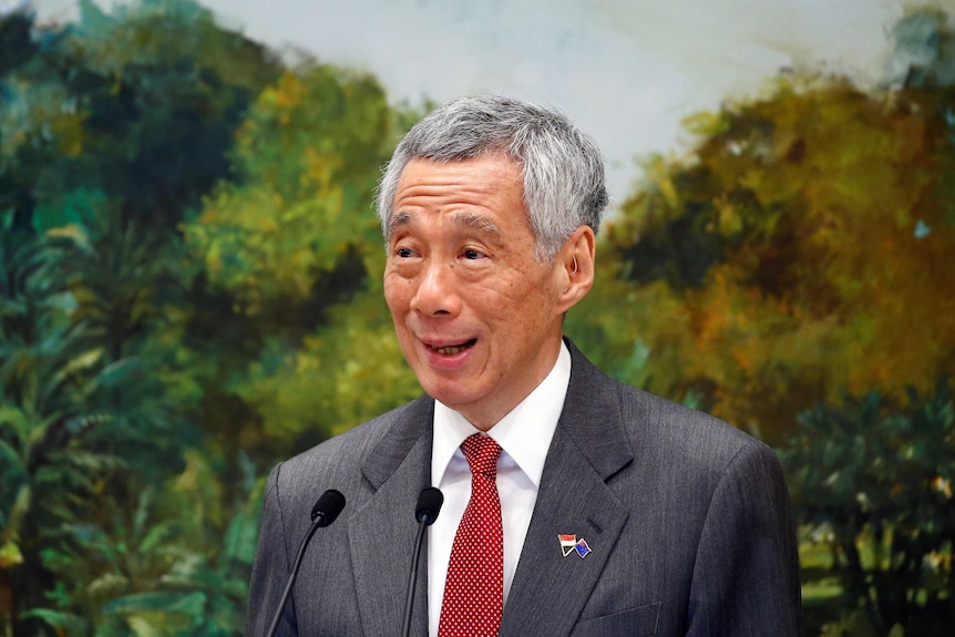 A man in a suit standing in front of a landscape painting