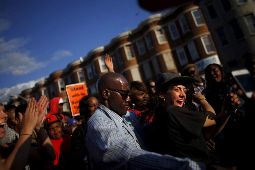 A group of smiling demonstrators dance on the street in Baltimore.