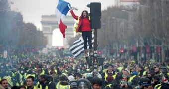 A protester wearing yellow vest stands on traffic lights on the Champs-Elysee in Paris.
