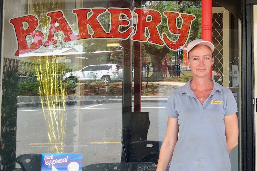 Woman in baseball cap stands outside bakery
