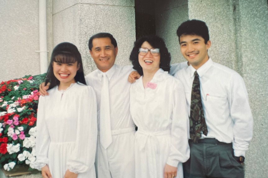 two men and two women all wearing white stand outside a church smiling