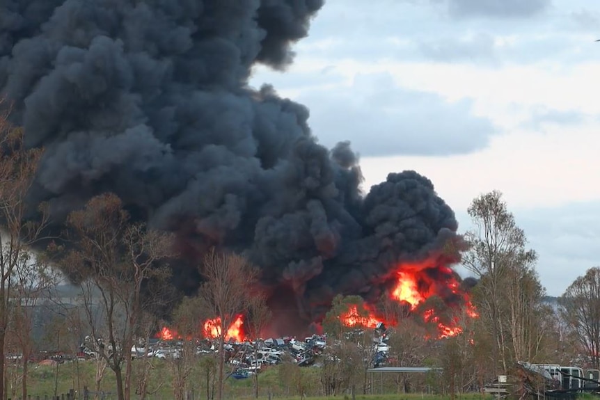 car yard on fire with large amount of dark smoke going into the air