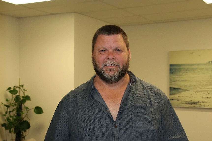 Child sex abuse survivor Peter is pictured in a room with a photo of the ocean in the background.