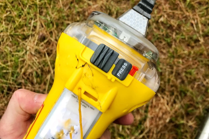 An expired emergency beacon held in someones hand. 