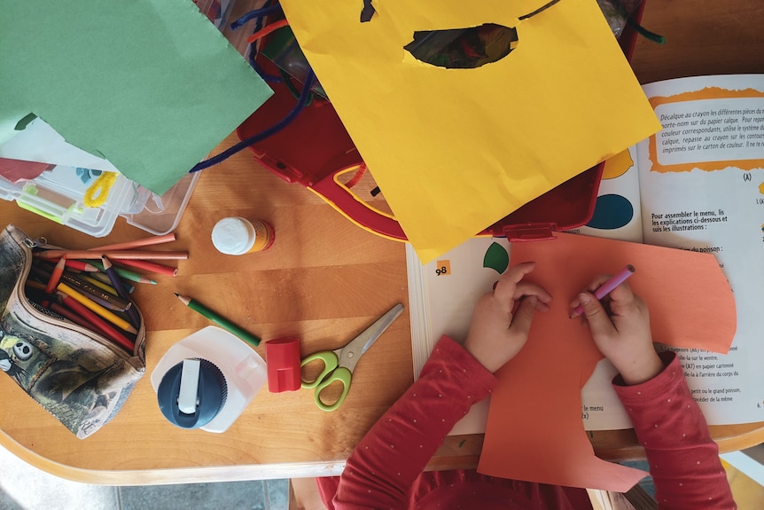 Bird's eye view of a child cutting up paper and working on homework. 