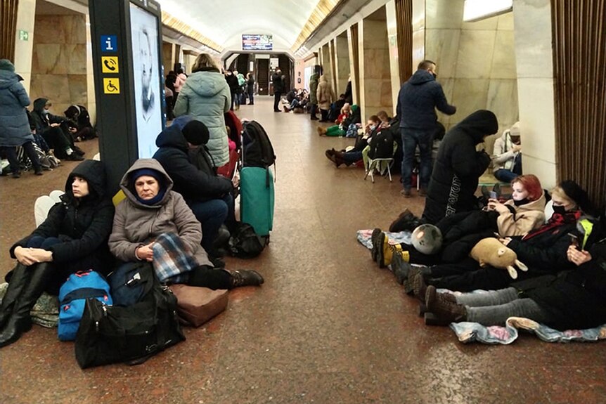 People sit slumped inside a subway with bundles in a makeshift bomb shelter
