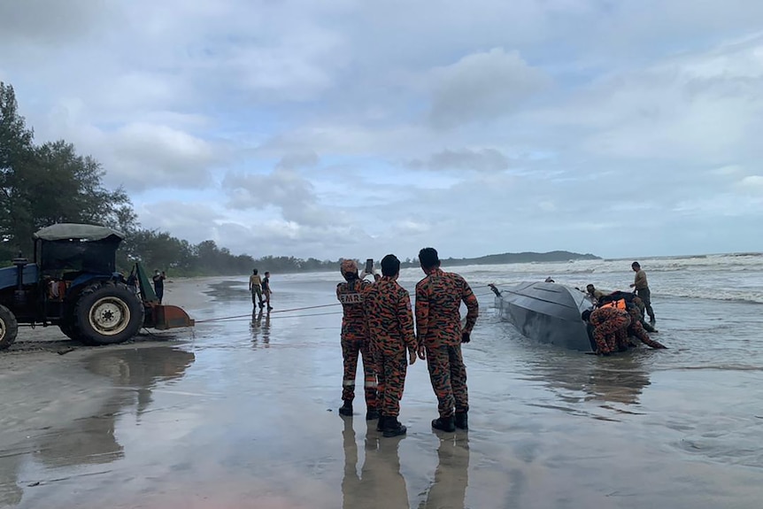 Armed forces inspect a capsized boat off the Malaysian coast