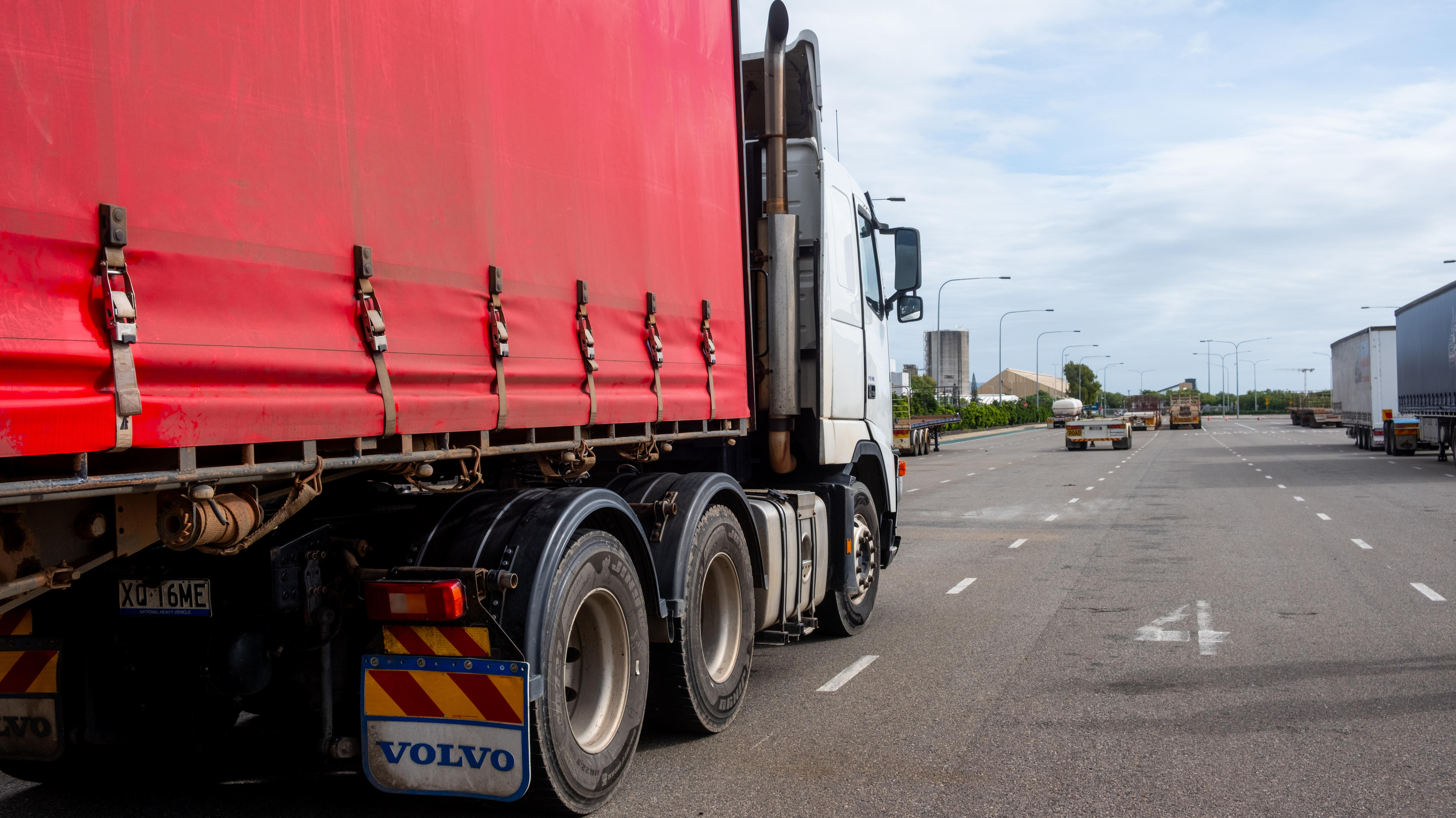 A truck lines up in a parking bay outside a busy coastal port