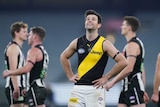 An AFL player smiles ruefully and looks to the sky after his team draws a match.
