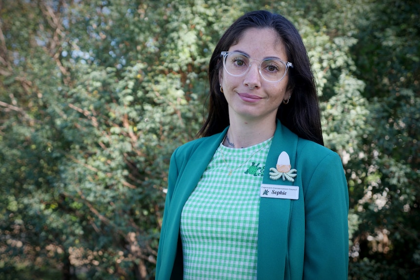 A woman with black hair and clear glasses smiles