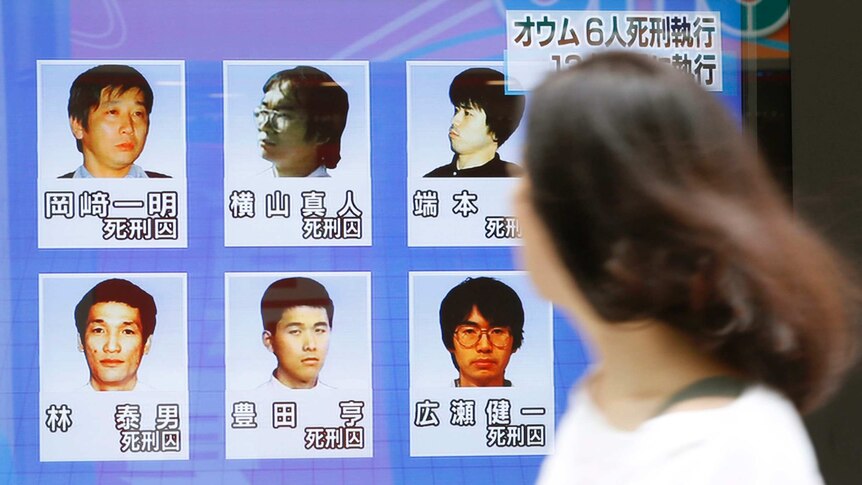 A woman walks past images of the last six Aum Shinrikyo members who have been executed.