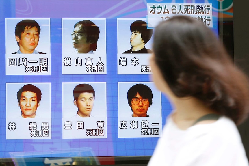 A woman walks past images of the last six Aum Shinrikyo members who have been executed.