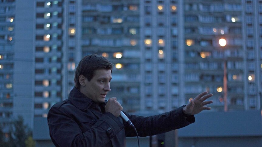 Mr Gudkov stands in front of a building addressing the crowd