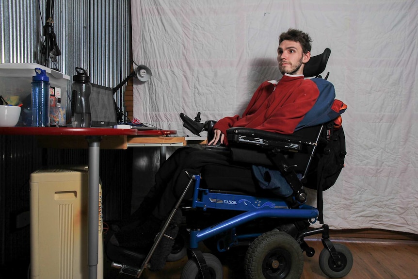 A man in a power wheelchair sitting in front of a screen
