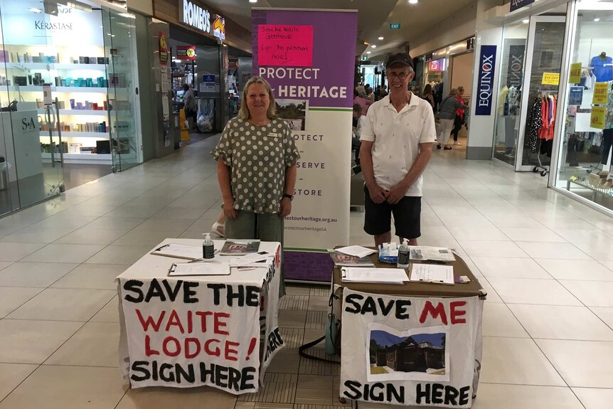 A man and woman stand in front of a petition table inside a shopping centre