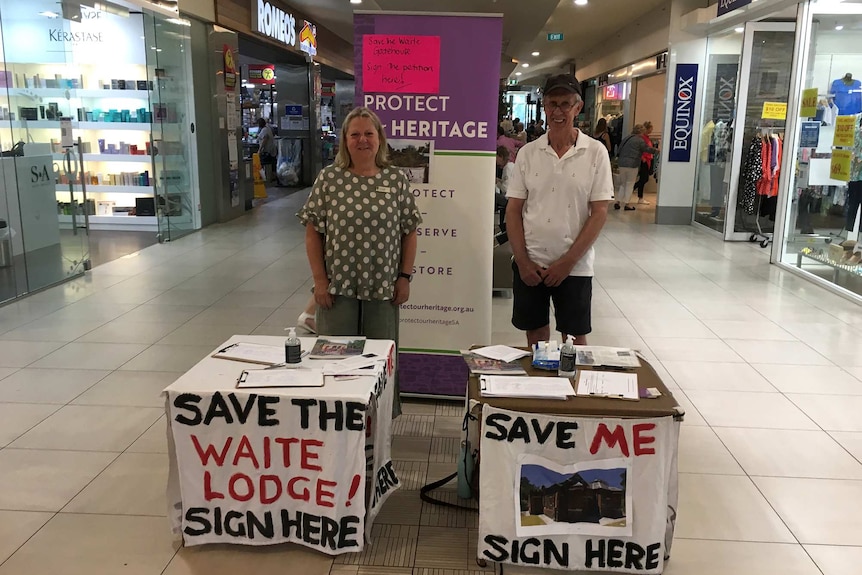 A man and woman stand in front of a petition table inside a shopping centre