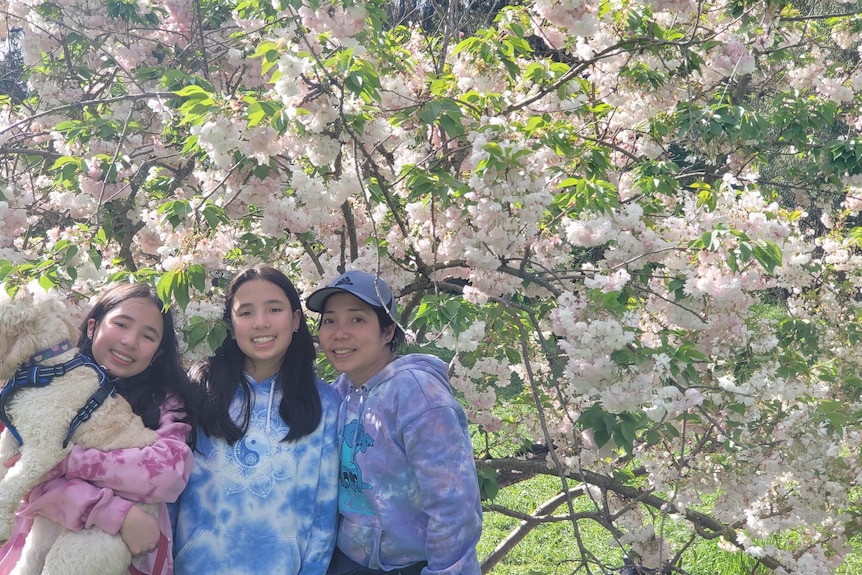 A woman and two identical twin girls pose for a photo.