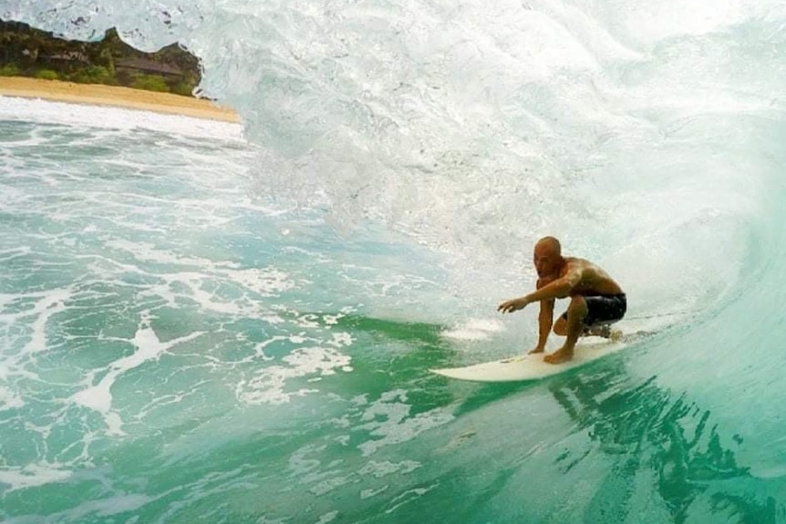 A male surfer inside the barrel of a wave.