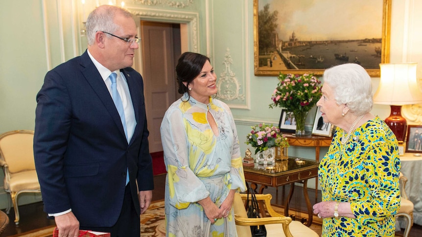 Queen wears bright yellow and blue pattern as she meets PM and his wife, PM holds a tartan patterned gift bag.