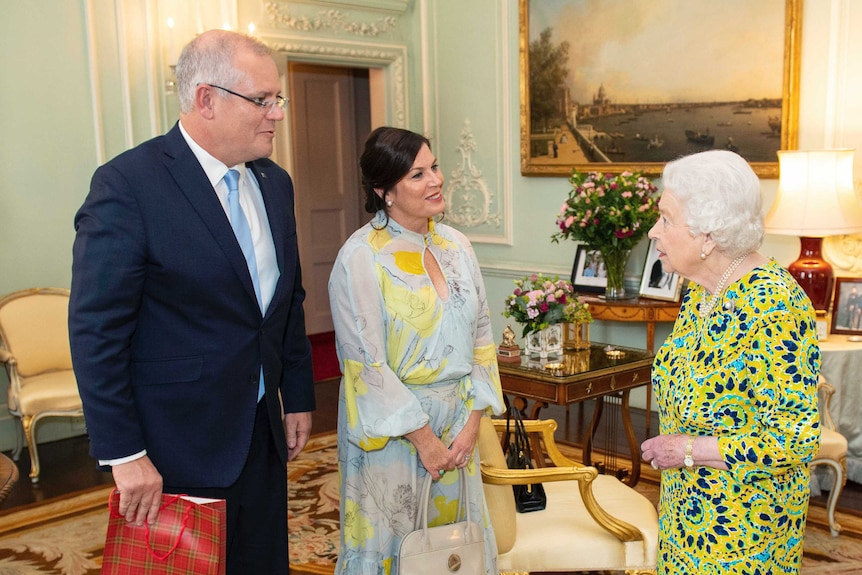 Die Königin trägt ein leuchtend gelbes und blaues Muster, als sie den Premierminister und seine Frau trifft. Der Premierminister trägt eine Geschenktüte mit Tartanmuster.
