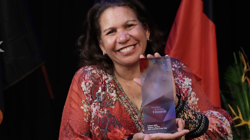 Leanne Liddle stands and smiles holding her NT Australian of the Year award.